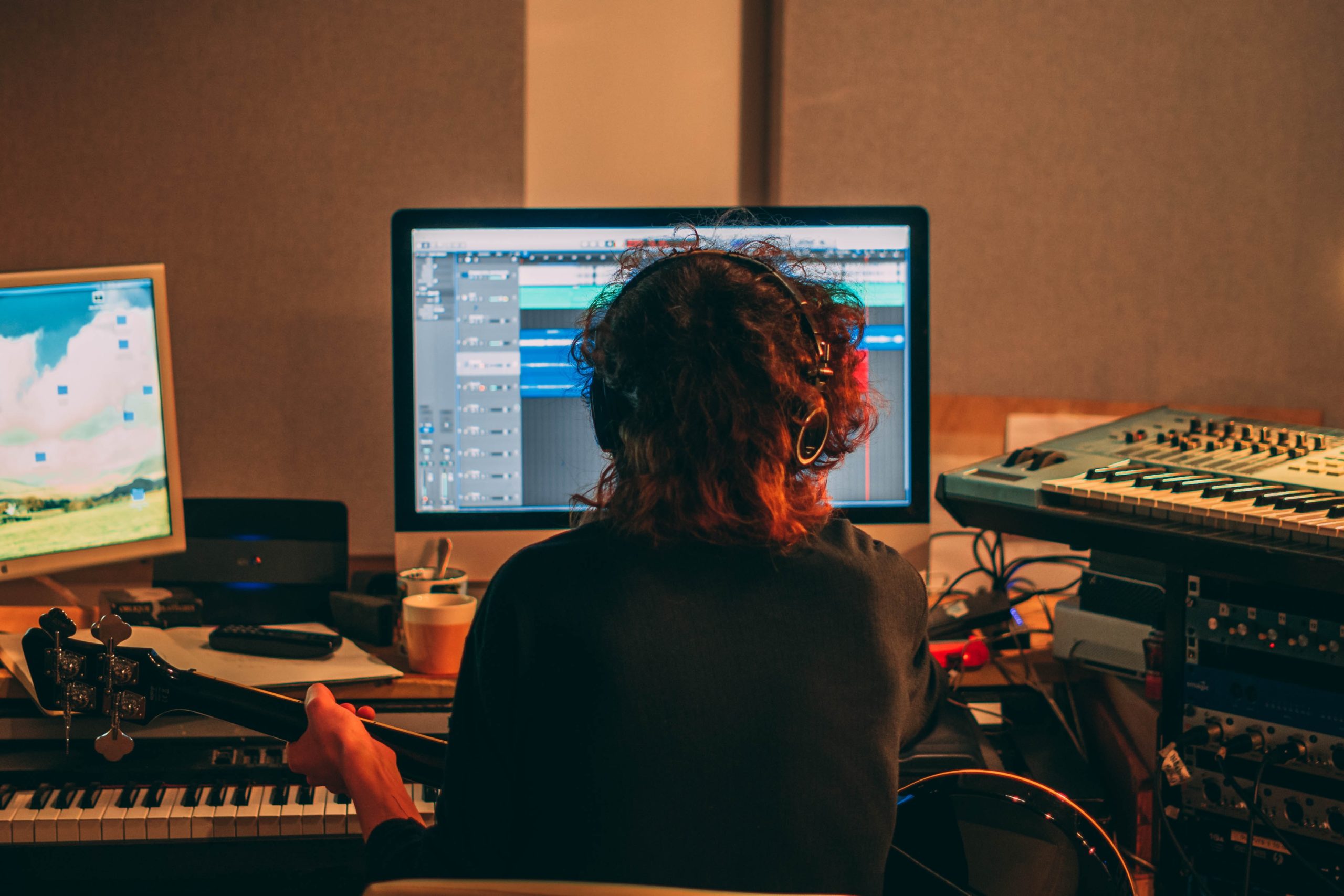 5G is the future of the music industry a musician sits in a home studio, holding a guitar and facing a computer