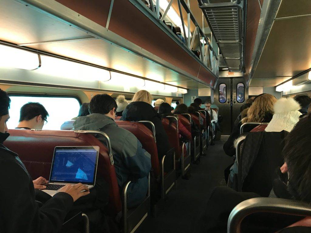 5G innovations can make for a better mass transit system Rows of train-riders use laptops and mobile devices.