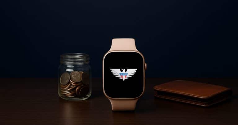 A smartwatch with the us mobile eagle on its screen on a desk beside a jar of coins and a leather wallet
