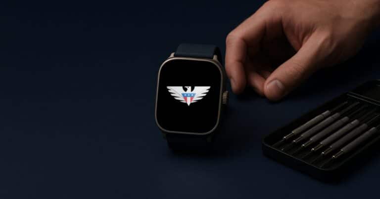 A smartwatch with the us mobile eagle on its screen on a workbench beside a precision screwdriver set